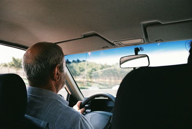 Een chauffeur aan het stuur, gezien van op de achterbank
